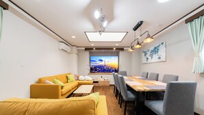 A modern living room with a sofa, dining table, and chairs, a flat-screen TV, and a world map artwork.