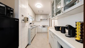 A modern kitchen with white cabinets, a black refrigerator, and a coffee machine.