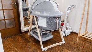 A room with a wooden floor, a baby stroller, a vacuum cleaner, and a door.