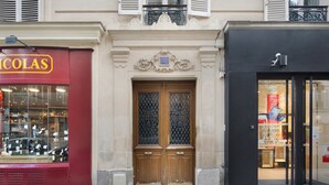 Ein Schaufenster mit einem roten Schild, einer hölzernen Doppeltür mit dekorierter Scheibe und einem schwarzen Schaufenster mit einem Schild.