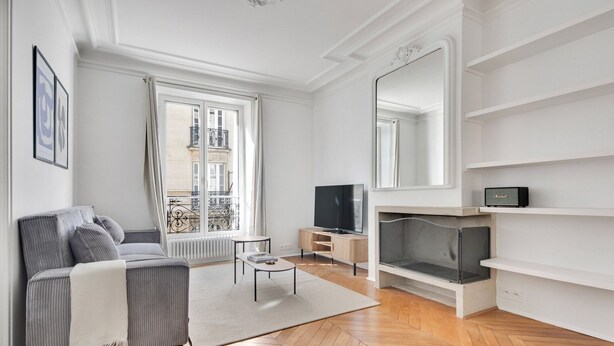 Ein modernes Wohnzimmer mit Sofa, Fernseher, Kamin und großen Fenstern.