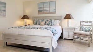 A bedroom with a bed, two bedside tables with lamps, a chair, and a ceiling fan. - Tamarind – 2BR Condo with Lemon Bay Views (Englewood)