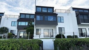 A modern multi-story residential building with a flat roof, large windows, and a white exterior. - Tamarind – 2BR Condo with Lemon Bay Views (Englewood)