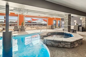 An indoor swimming pool with a hot tub, stone walls, and outdoor seating area. - Lake Front Rooftop Hot Tub Game Room Escape (Branson)