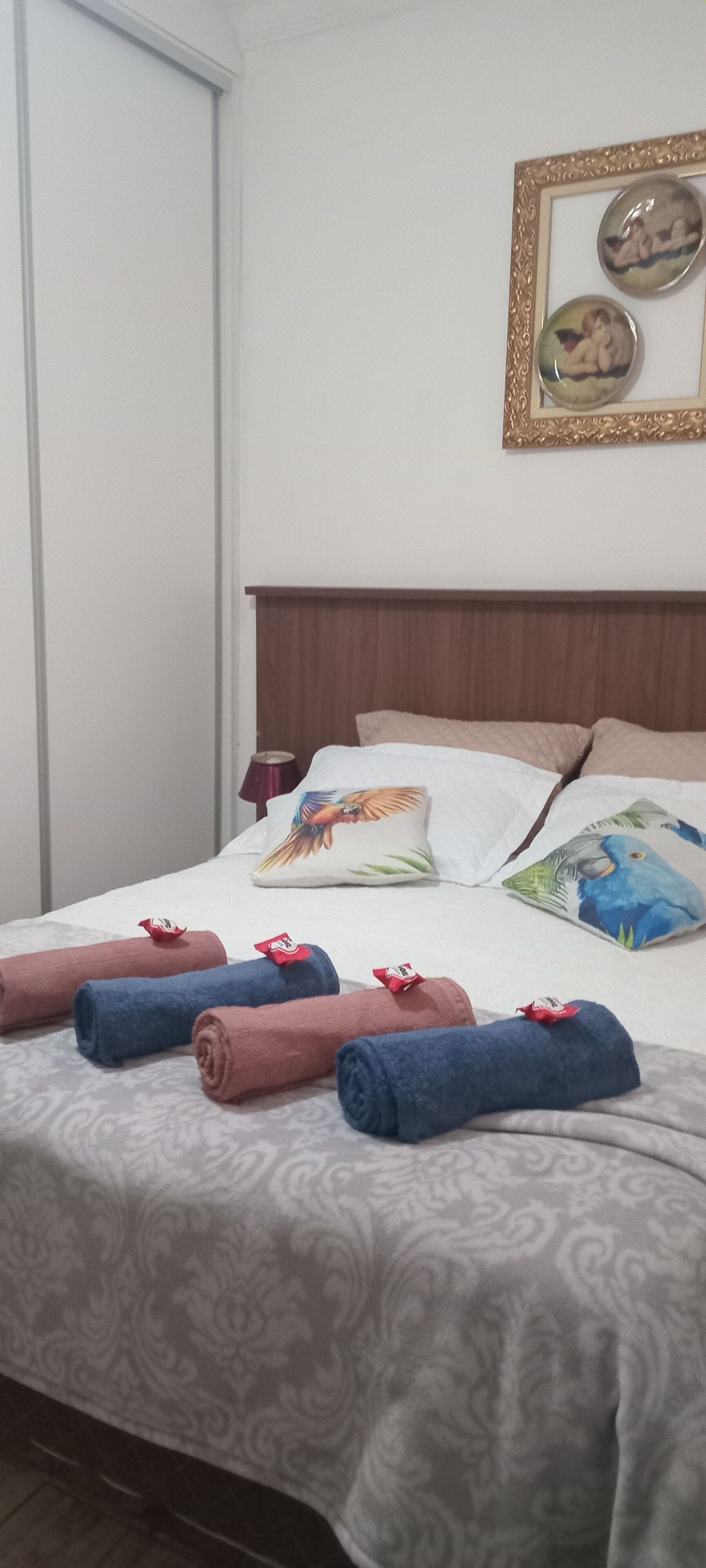 A neatly made bed with rolled towels, a wooden headboard, and decorative pillows.