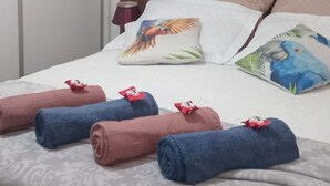 A neatly made bed with rolled towels, a wooden headboard, and decorative pillows. - Beautiful beachfront apartment in a prime location in Santos for you and your pet. (Santos)