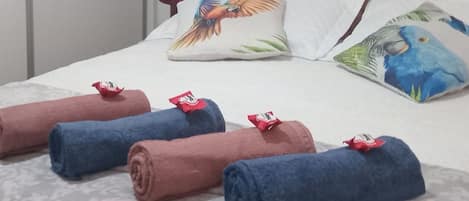 A neatly made bed with rolled towels, a wooden headboard, and decorative pillows.