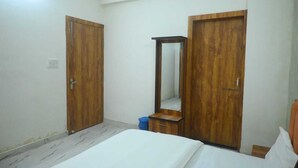 Une chambre à coucher avec un lit, deux armoires en bois et un miroir.