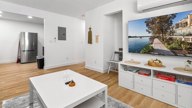 A modern living room with a white sofa, a flat-screen TV, and a built-in cabinet with board games. - Casitas en Pueblo - Central Lofts (Pueblo)