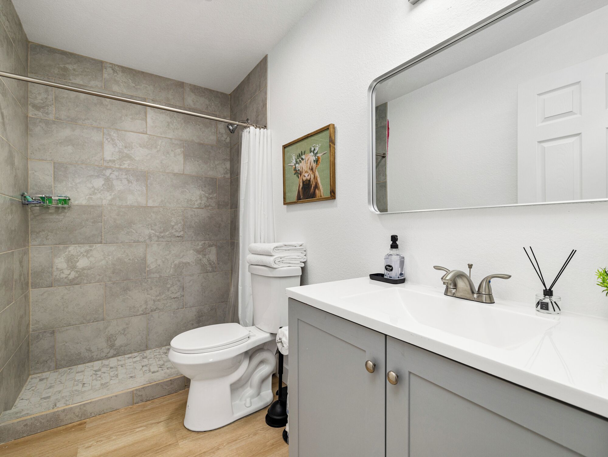 A modern bathroom with a shower, toilet, and sink.