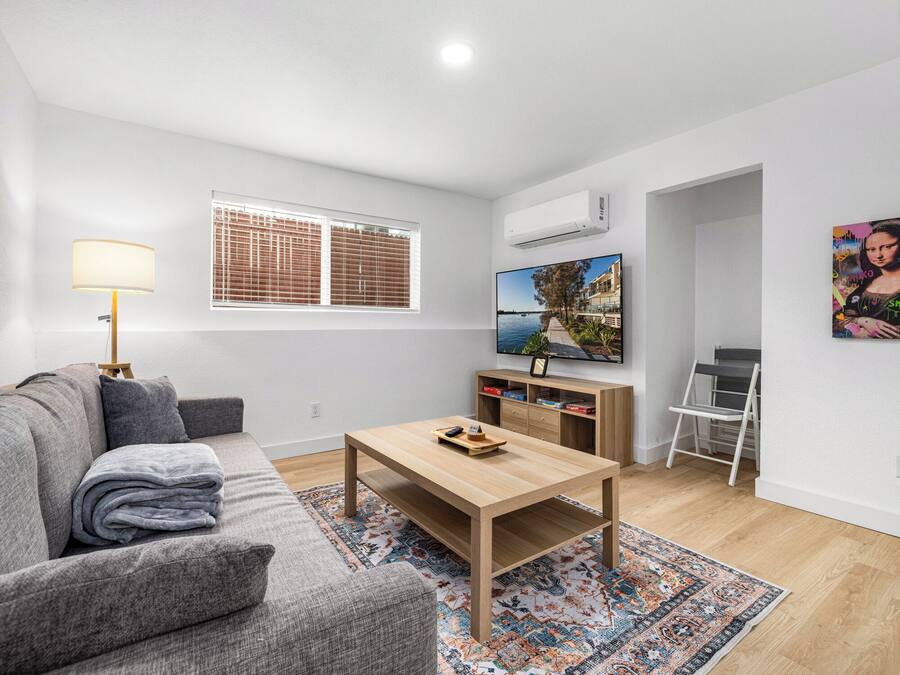 A modern living room with a sofa, coffee table, TV, and a ladder.