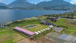 A lakeside property with a large building, a greenhouse, and a parking area. - Butterfly Bali Glamping (Baturiti)
