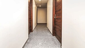 A hallway with wooden doors on both sides and a grey carpeted floor. - Hotel Shiv Kripa (Kanpur)