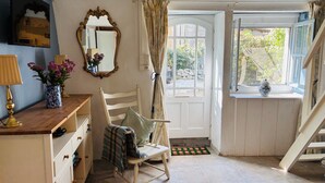 A cozy room with a wooden chair, a small table with a lamp, a mirror, and a window with curtains. - 2 Bedroom Cottage - Sleeps 6 - Pool - Garden (Caylus)