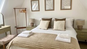 A neatly arranged bedroom with a bed, bedside tables, a hanging chair, and three framed artworks on the wall. - Central Tenby 3 Bed Apt Sleeps 6 to 8 Dog Friendly (Pembrokeshire)