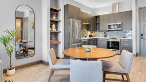 Una cocina moderna con gabinetes oscuros, electrodomésticos de acero inoxidable y una mesa redonda con sillas.