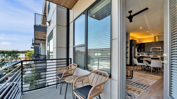 Un apartamento moderno con balcón, ventanas amplias y zona de cocina.