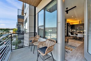 Un appartement moderne doté d’un balcon, de grandes fenêtres et d’un coin cuisine.