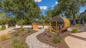 Um jardim com estrutura de barril de madeira, um caminho sinuoso e diversas plantas.