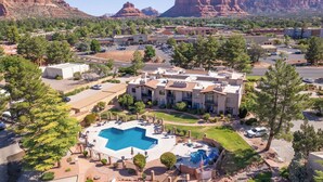 A resort with a swimming pool, multiple buildings, and a mountainous backdrop.