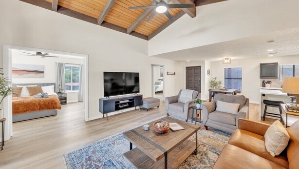 A spacious living room with a large TV, comfortable seating, and a wooden ceiling.