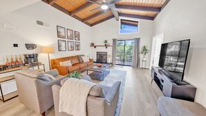 A spacious living room with a high ceiling, a fireplace, a television, and a coffee table.