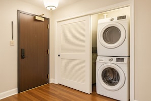 A laundry room with a wooden door and two stacked washing machines.