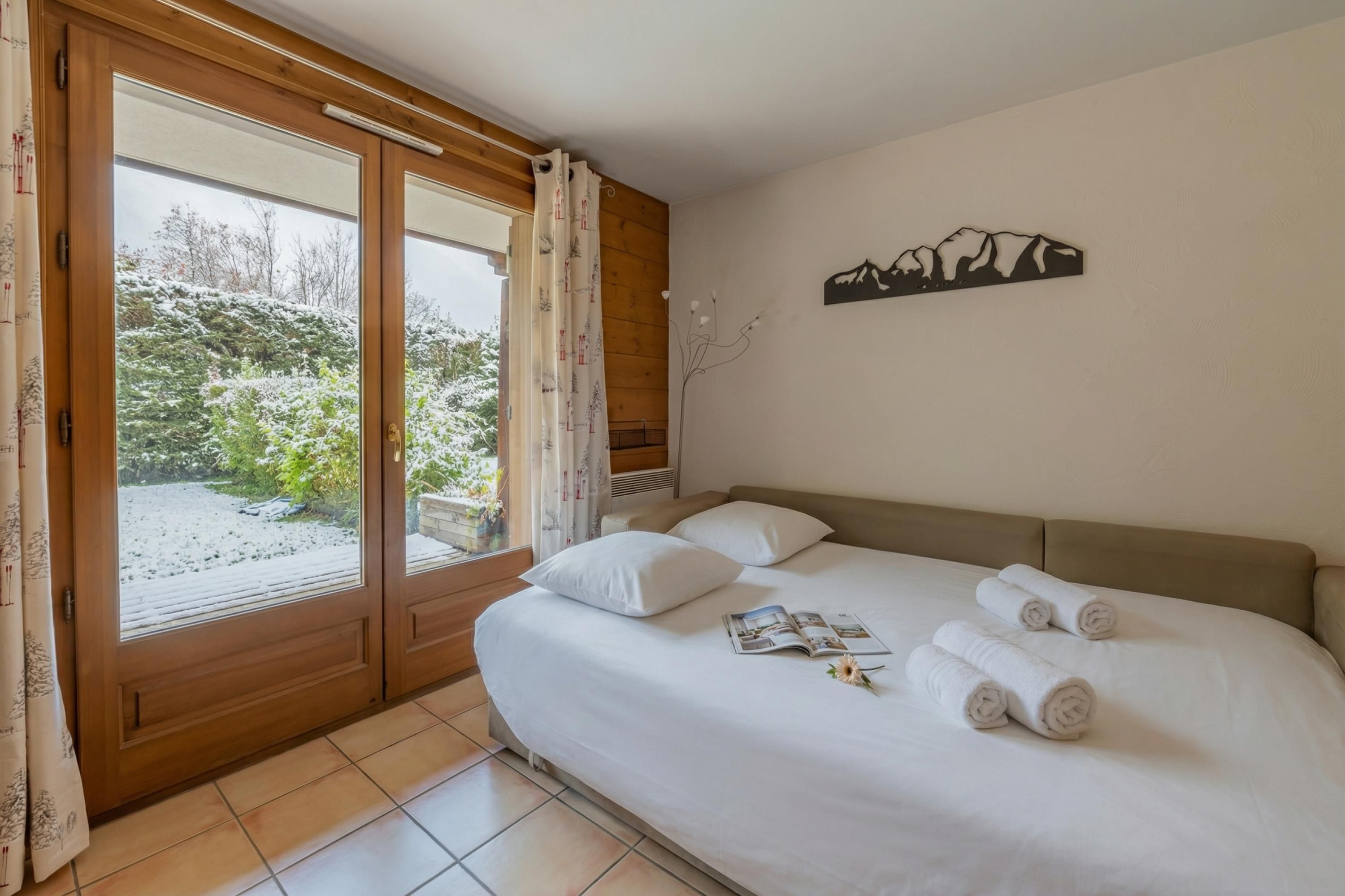 A bedroom with a bed, pillows, a magazine, and towels.