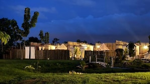 Un espace extérieur clos, agrémenté de plusieurs structures en bois, peut-être des chambres d’hôtes ou des chalets, sous un ciel sombre.