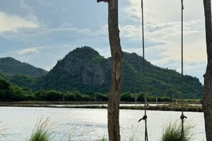 Een natuurlijk landschap met een waterpartij, bomen en een berg op de achtergrond.