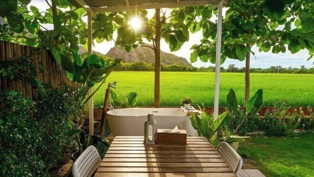 Une terrasse en bois avec une table, des chaises et une baignoire.