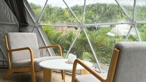 Une tente avec vue sur la verdure, deux chaises et une petite table.