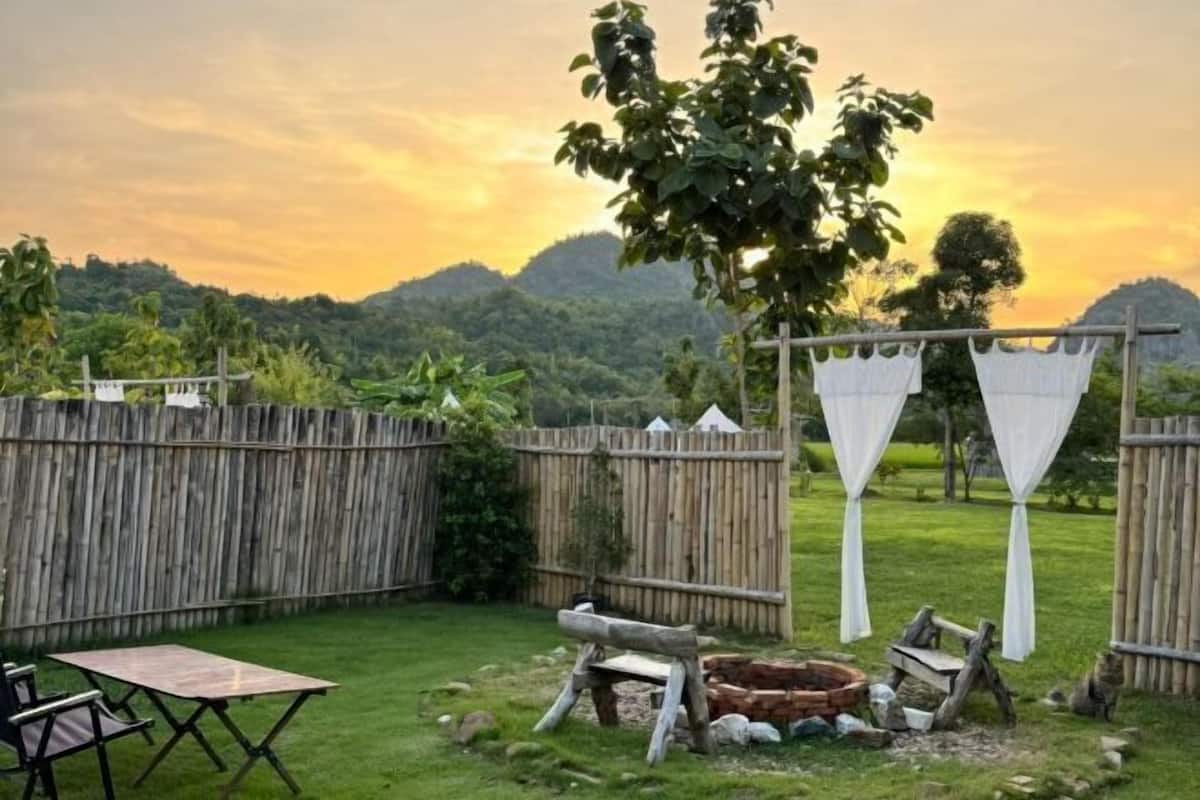 A backyard with a wooden fence, a table, chairs, and a fire pit.