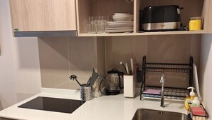 Eine moderne Küche mit Holzschränken, einer schwarzen Mikrowelle, einem Spülbecken und einer Kaffeemaschine.