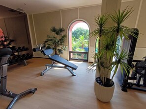 A gym with exercise equipment, a bench, and potted plants.