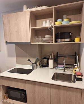 Una cocina moderna con gabinetes de madera, un microondas negro, un fregadero y una cafetera.