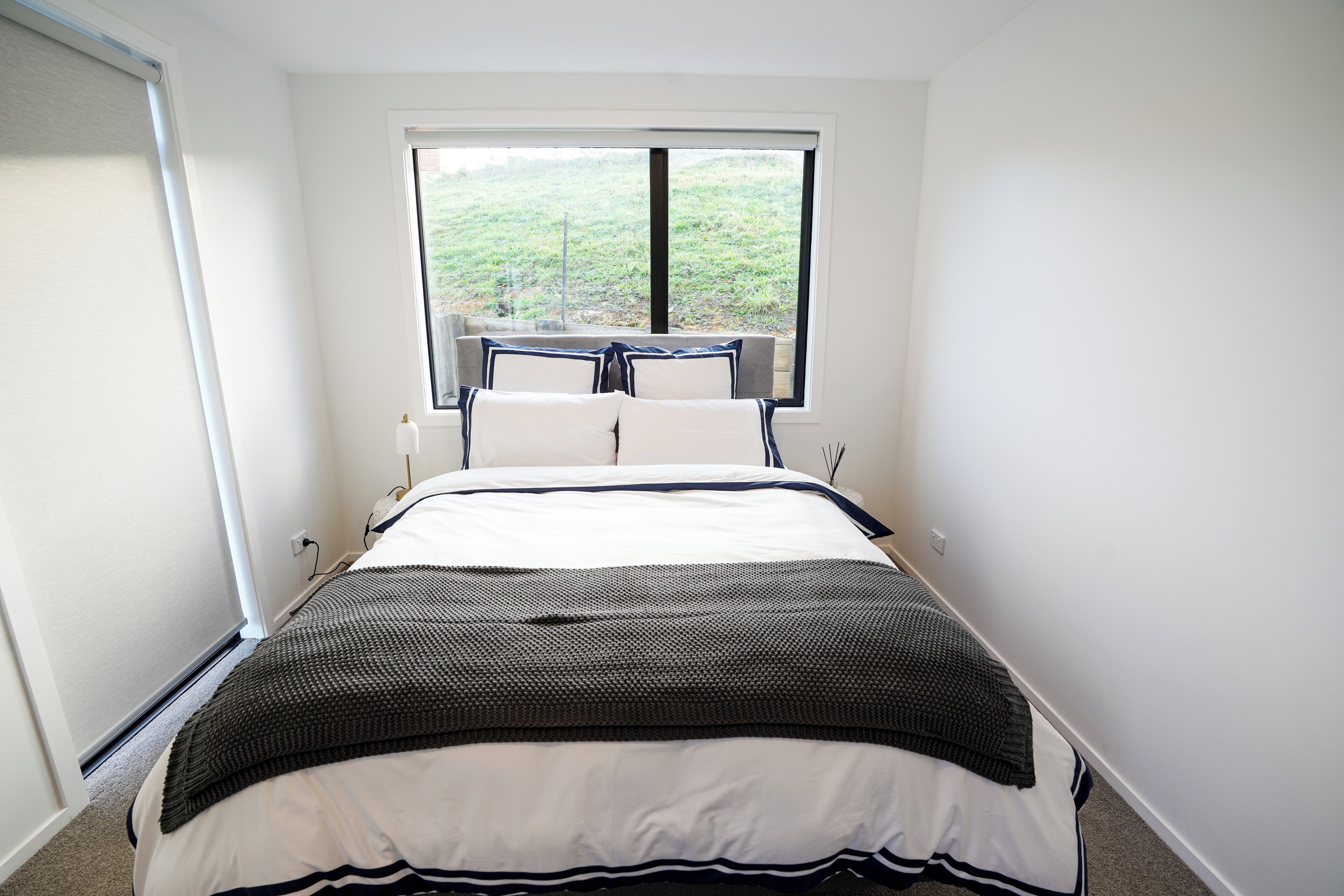 Un dormitorio con una cama grande, una ventana con vistas a la vegetación y una pequeña mesa con sillas.