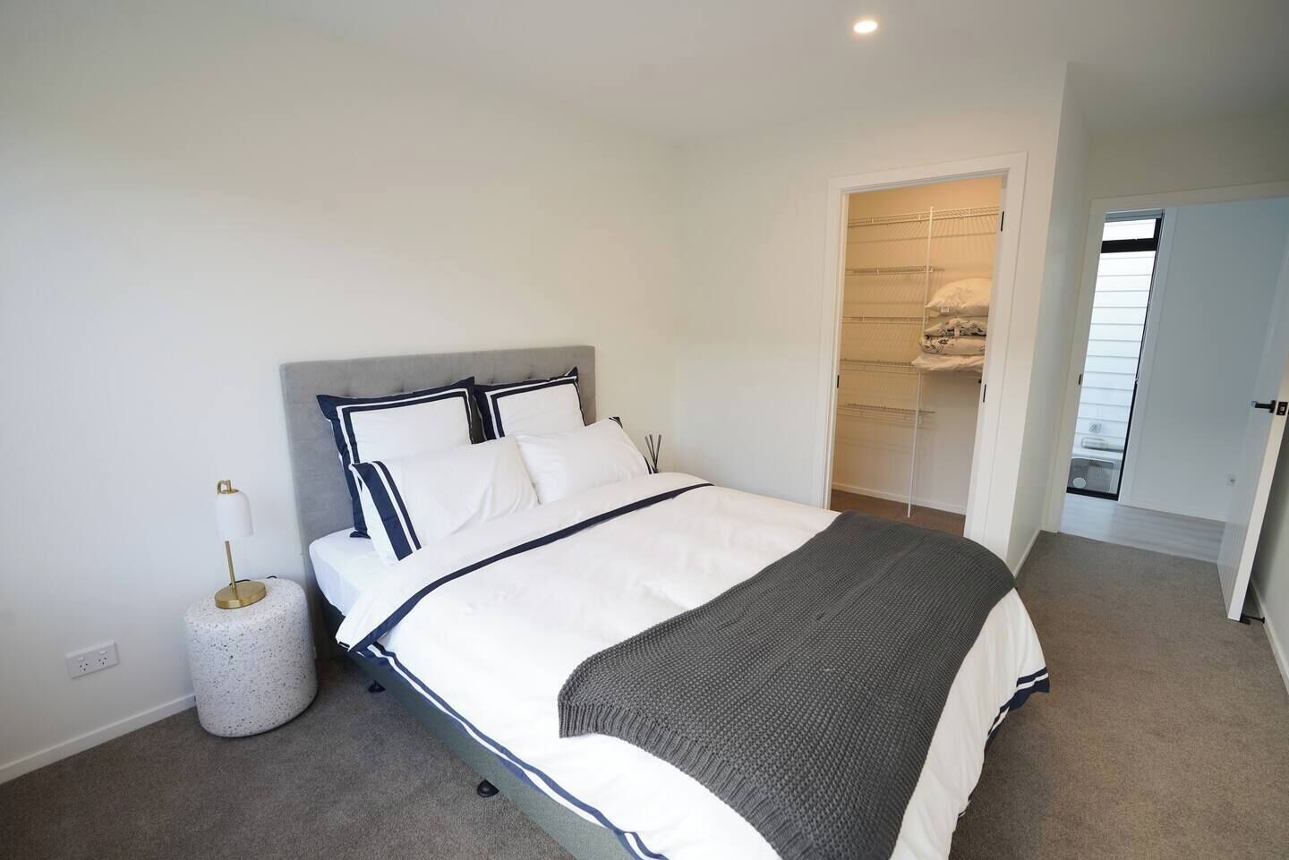 A neatly arranged bedroom with a bed, bedside lamp, and a small round table.