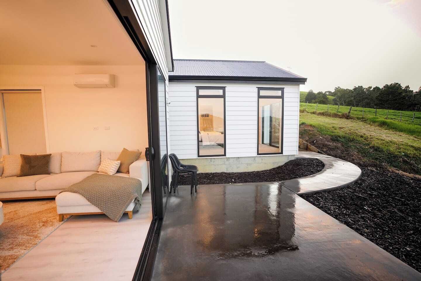 A modern house with a large sliding glass door leading to a patio.