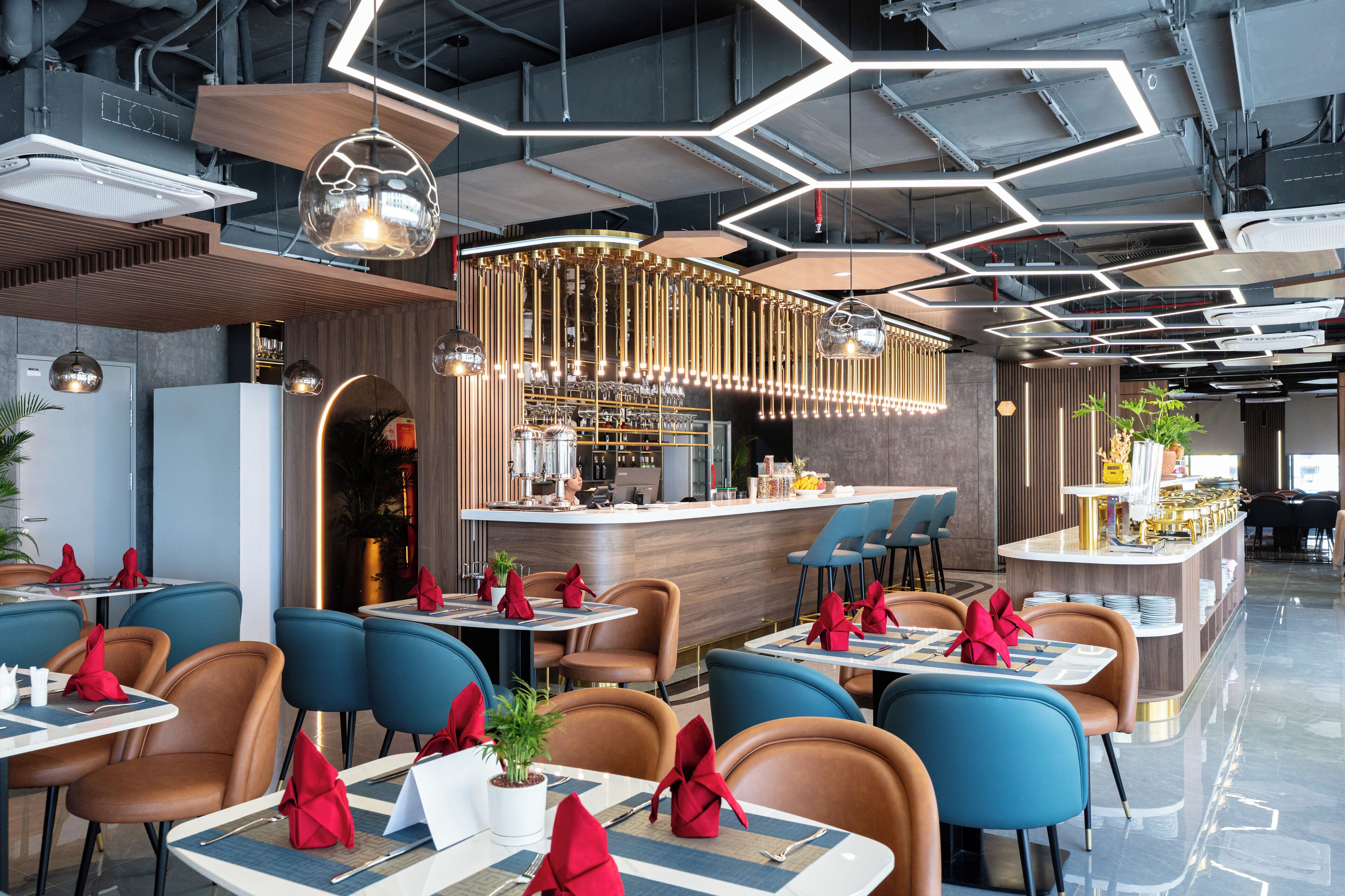 Un restaurante moderno con una barra central, sillas azules y marrones, y un diseño de techo geométrico.