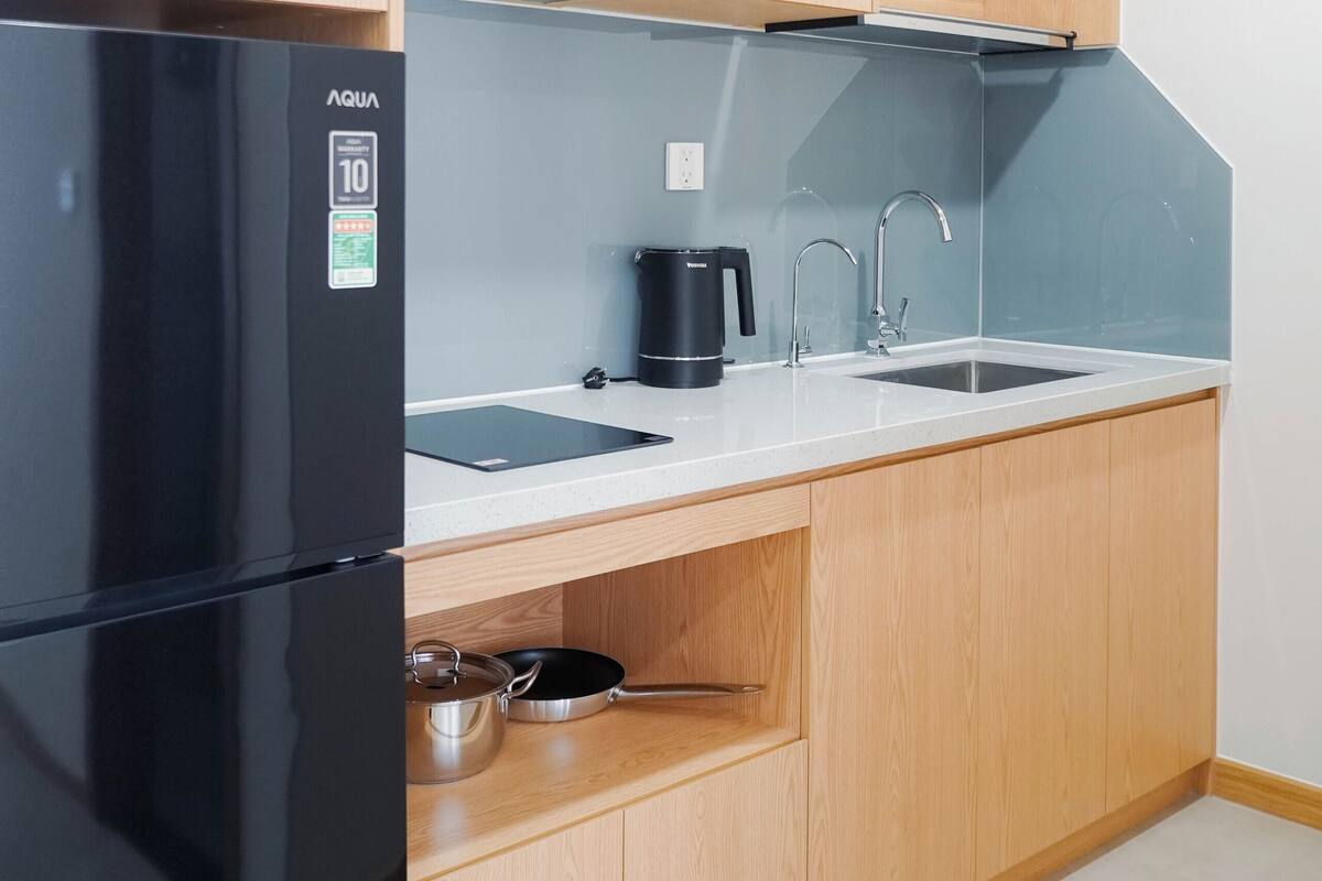 A kitchen with wooden cabinets, a black refrigerator, a sink, and a stove.