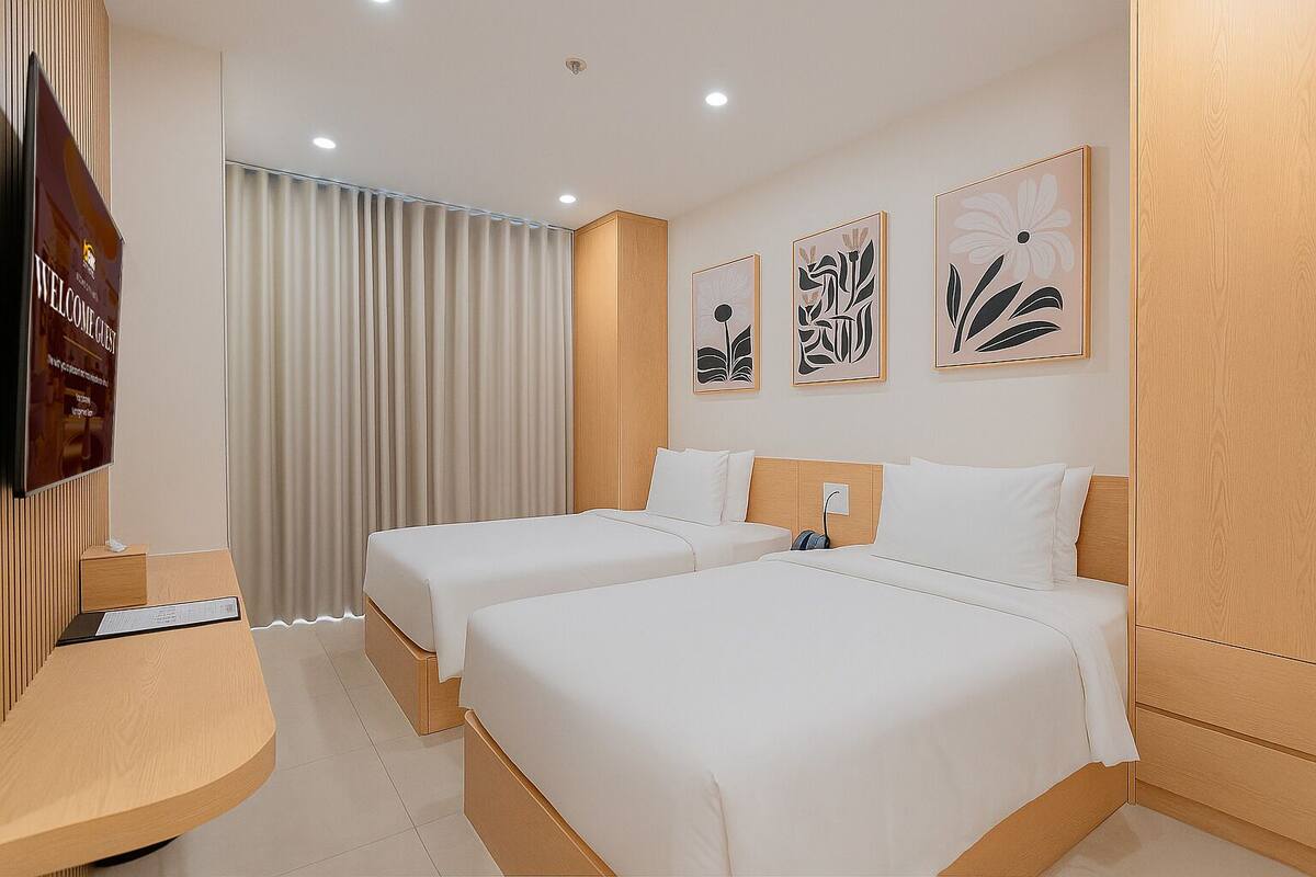 A hotel room with two beds, a TV, and artwork on the wall.