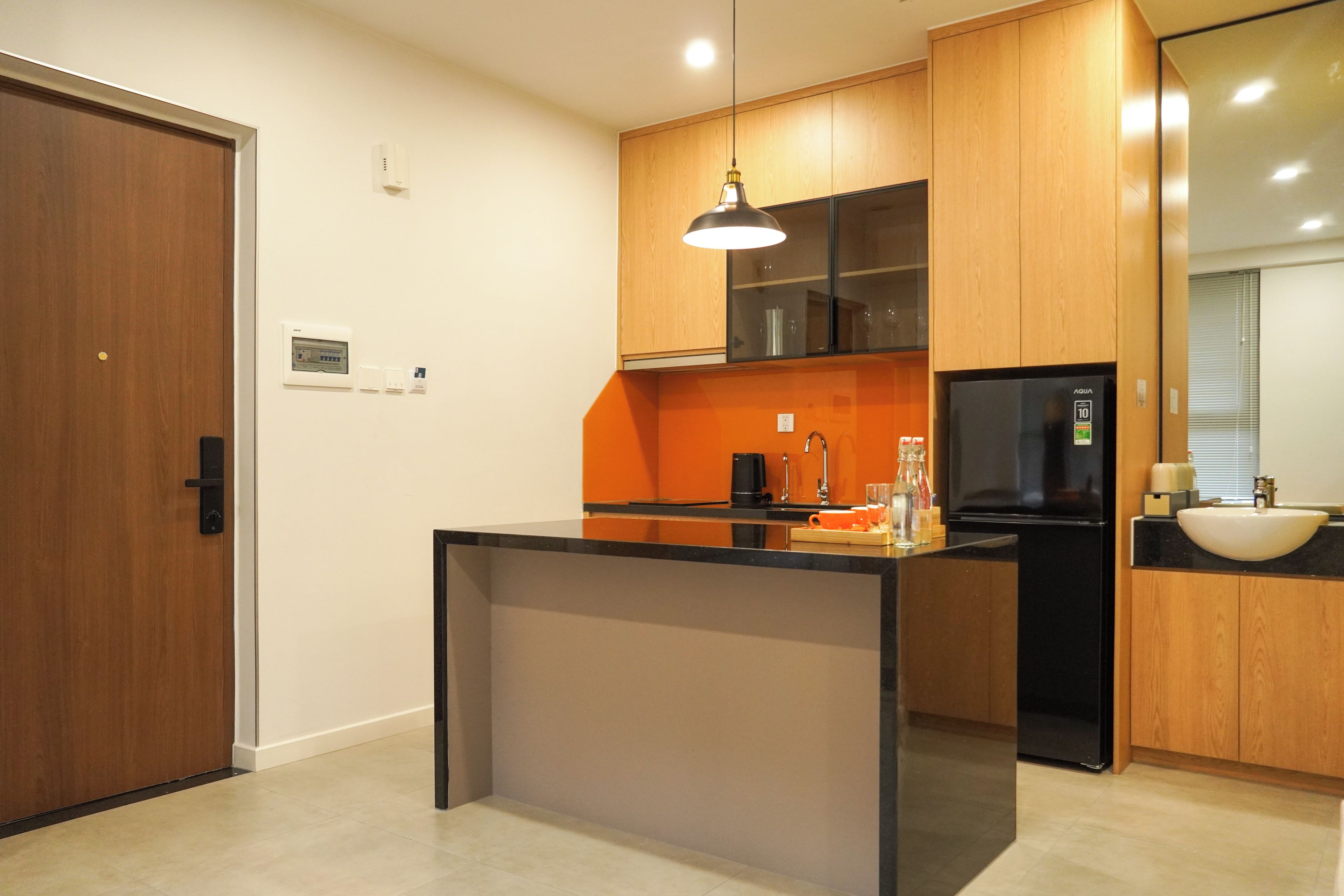 A modern kitchen with a central island, black appliances, and wooden cabinetry.