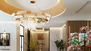 A modern lobby with a large chandelier, a round table with a vase of flowers, and a seating area with chairs. - Bcons City Hotel (Ho Chi Minh City)