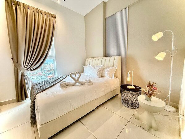 Una habitación de hotel moderna con una cama grande, una mesita de noche con lámpara y vistas a la ciudad a través de la ventana.