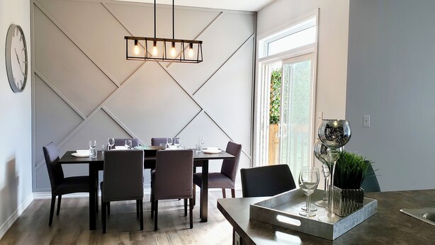 A modern dining area with a rectangular table, six chairs, and a hanging light fixture.