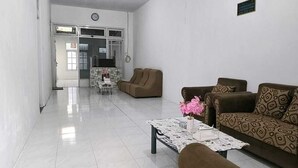 Ein geräumiges Wohnzimmer mit einer Sofagarnitur, einem Couchtisch mit einer Vase und einem Essbereich im Hintergrund.