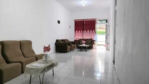 Ein Wohnzimmer mit einem braunen Sofa, einem gemusterten Sofa und einem kleinen Tisch mit einer Vase.