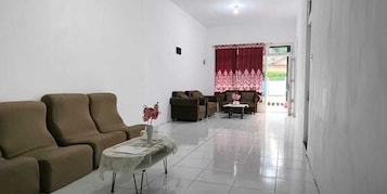 Uma sala de estar com um sofá marrom, um sofá estampado e uma mesa pequena com um vaso.