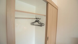 Une armoire avec une structure en bois, une porte en verre et une tringle en métal pour suspendre les vêtements.
